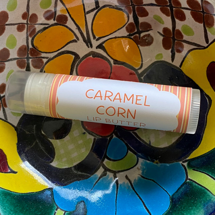 Lip butter labeled 'Caramel Corn' on a colorful ceramic plate