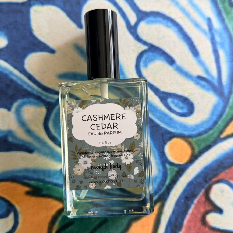 Perfume bottle labeled 'Cashmere Cedar' on a colorful patterned background