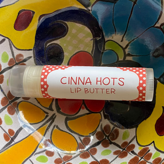 Lip butter with 'Cinna Hots' label on a colorful floral plate
