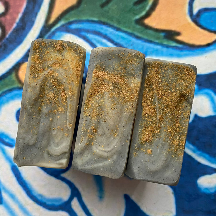 Three rectangular soap bars with a marbled pattern on a colorful ceramic surface