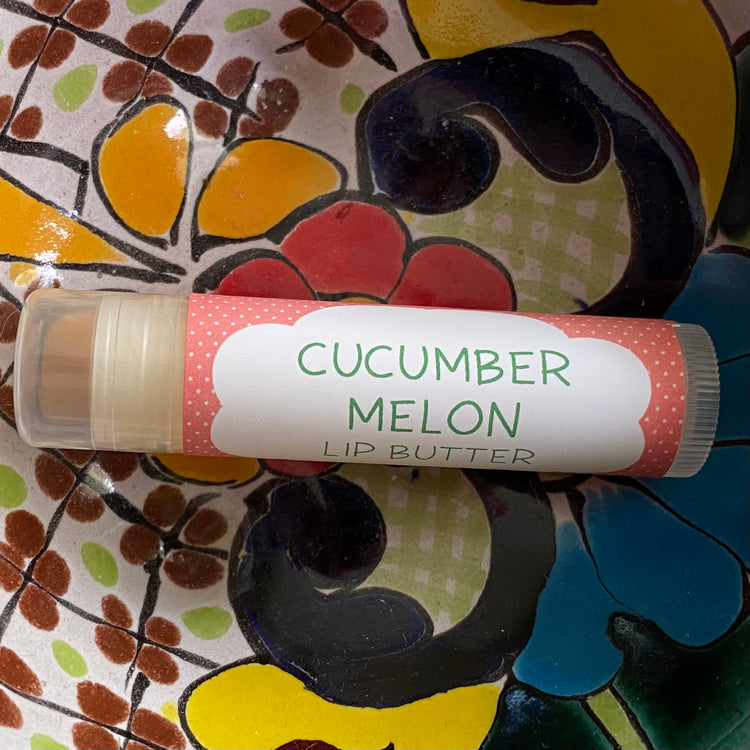 Lip butter labeled 'Cucumber Melon' on a colorful floral plate