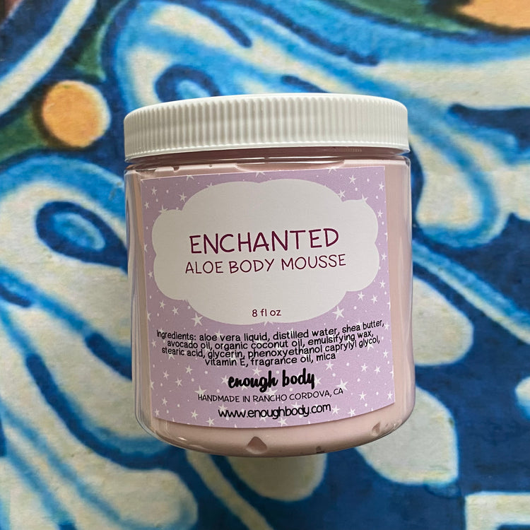 Jar of Enchanted Aloe Body Mousse with a colorful abstract pattern in the background