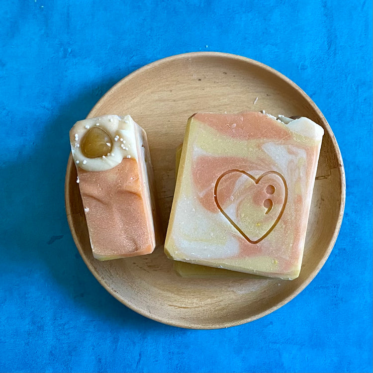 Yellow and orange square shaped soap bar on a plate sitting on a blue background
