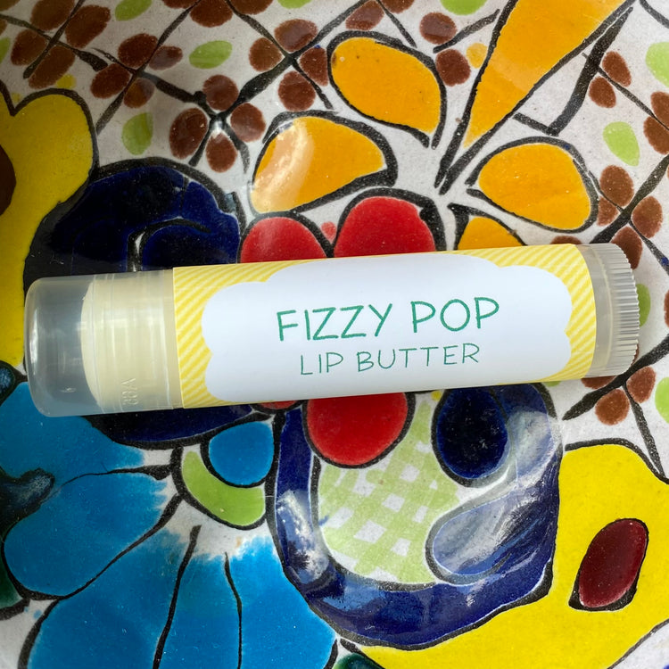A tube of fizzy pop lip butter on a colorful background
