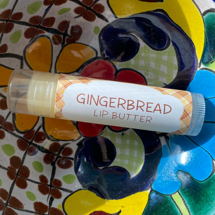 A tube of Gingerbread Lip Butter placed on a colorful patterned surface.