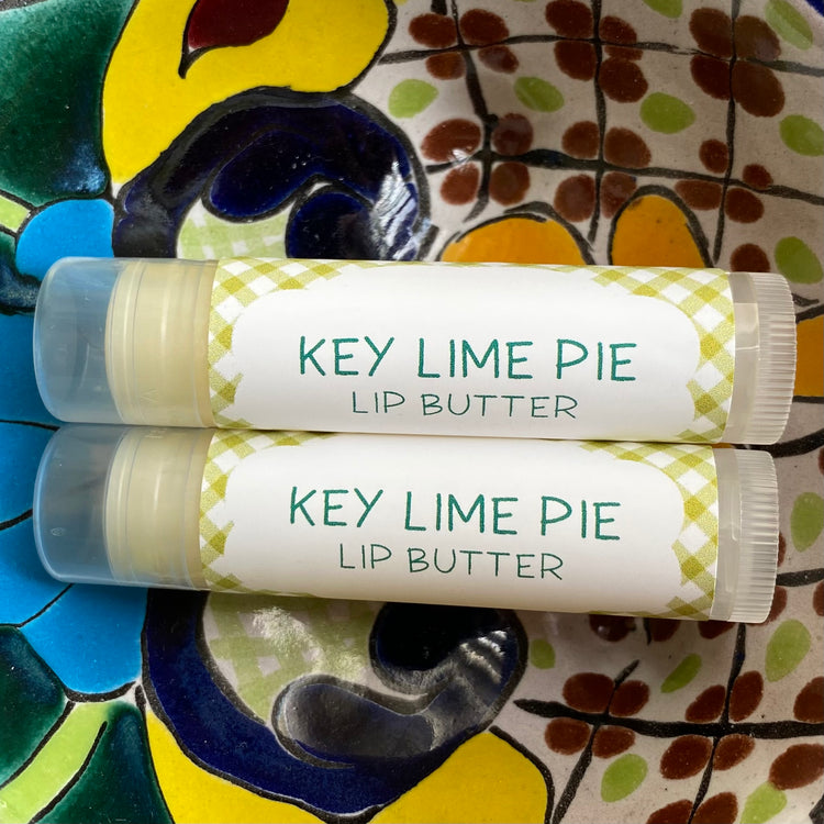 Two tubes of Key Lime Pie Lip Butter placed on a colorful ceramic plate with a geometric pattern.