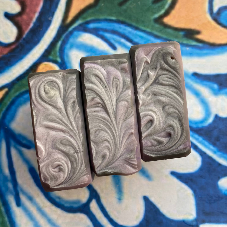 Three marbled soap bars on a colorful ceramic surface