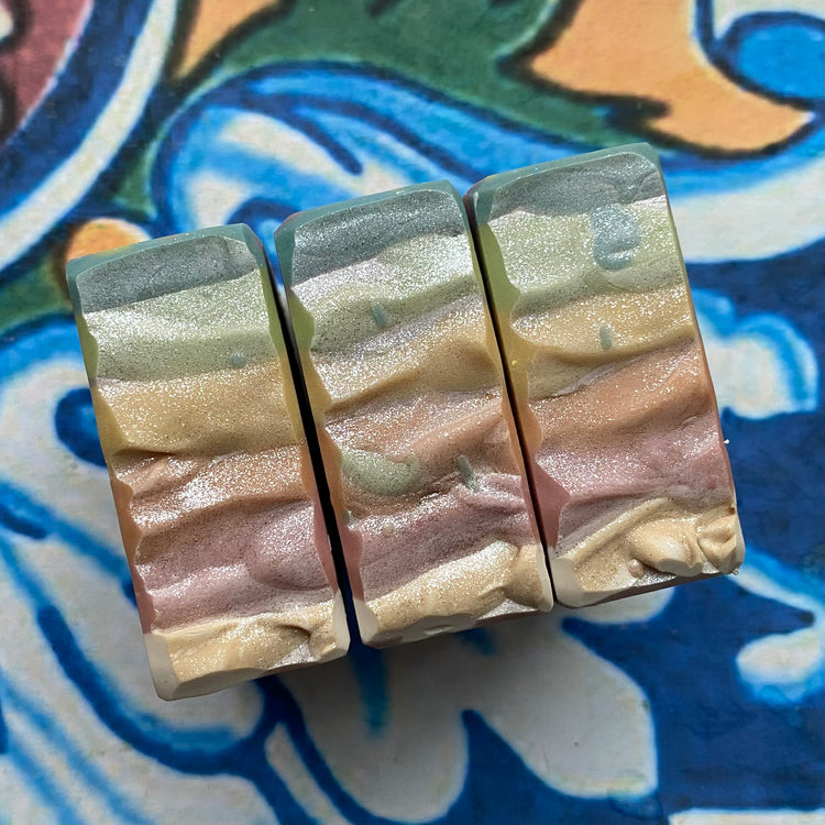 Three bars of soap with a multicolored pattern on a decorative tile background