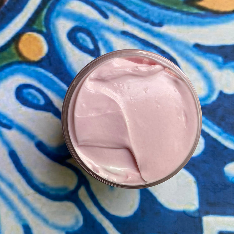 Pink cream in a jar on a colorful patterned fabric background