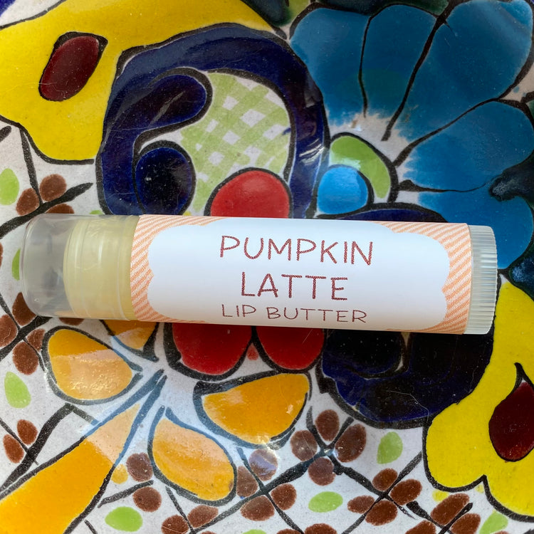 Lip butter labeled 'Pumpkin Latte' on a colorful ceramic plate with floral patterns