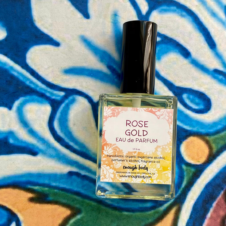 Perfume bottle labeled 'Rose Gold Eau de Parfum' on a colorful abstract background