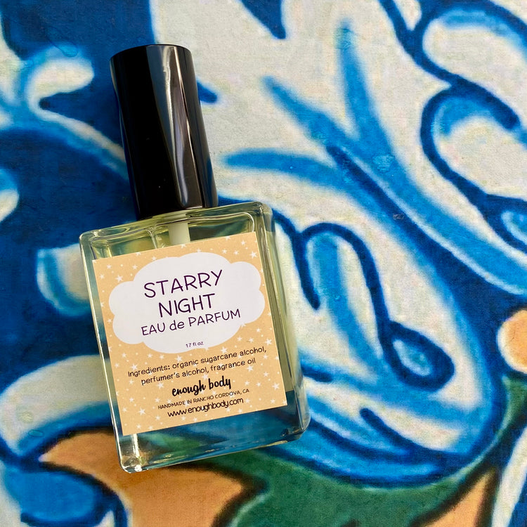 A glass bottle of Starry Night Eau de Parfum spray with a black spray mister top, labeled with the product name and a blue, green, and yellow artistic background.