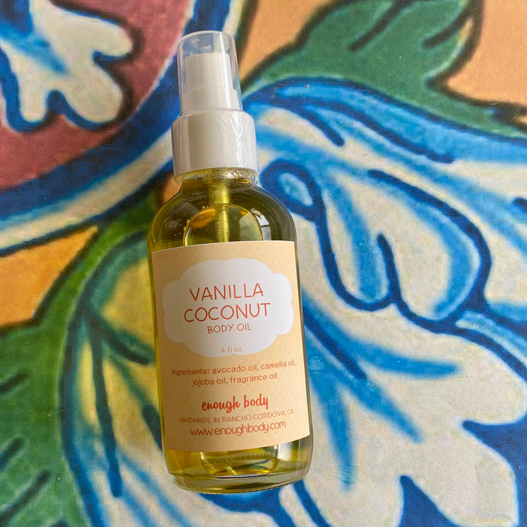 Bottle of Vanilla Coconut body oil with a treatment pump top on a colorful abstract background