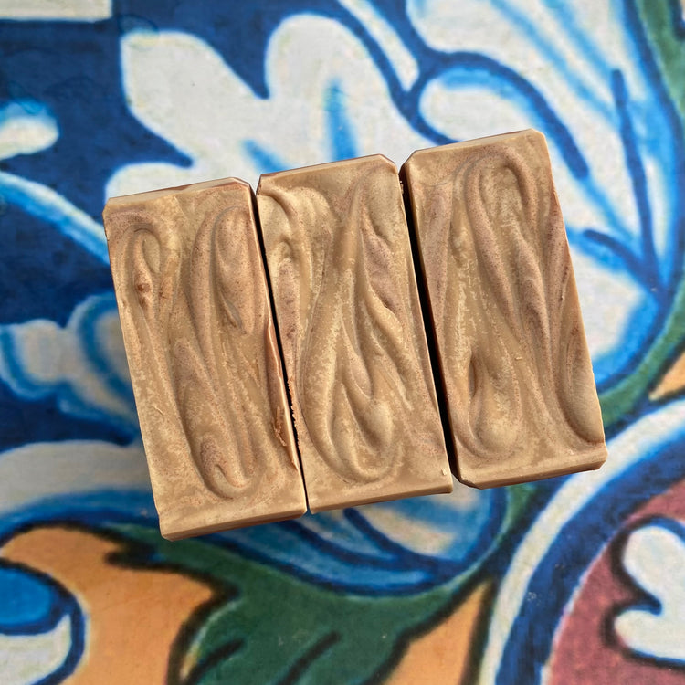 Three rectangular soap bars with a wavy texture on a colorful patterned background