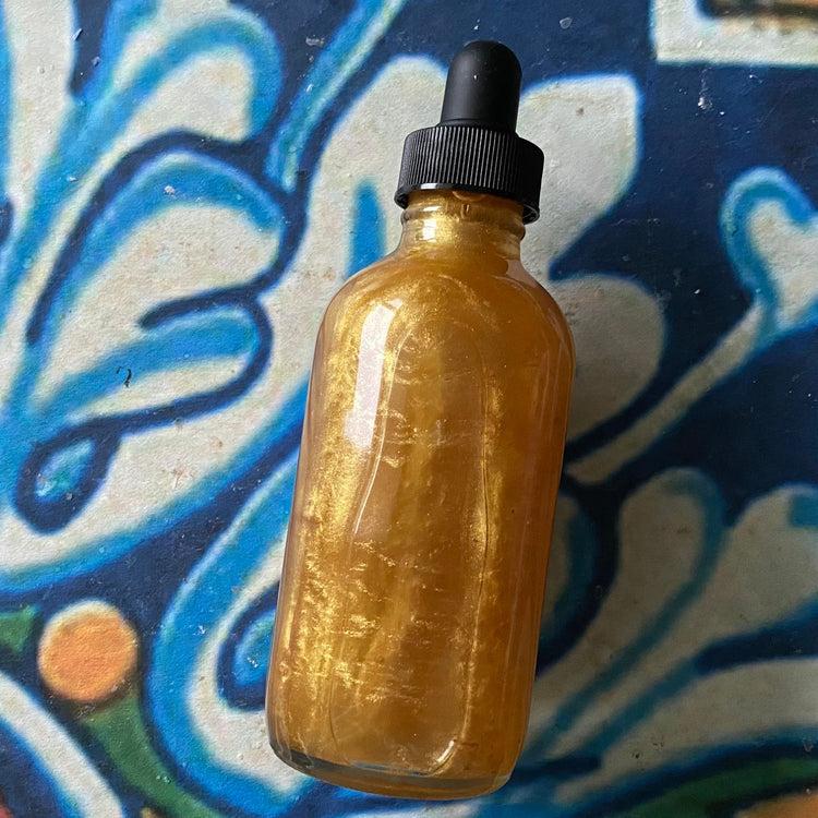 Bottle of oil with gold shimmer liquid on a colorful abstract background