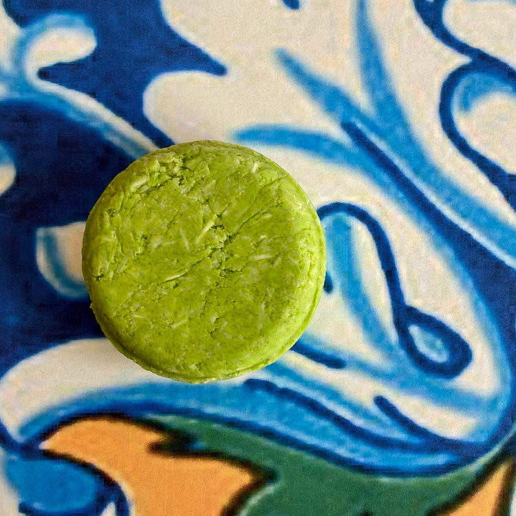 A solid shampoo bar on a patterned background, with a focus on the product's texture and color.