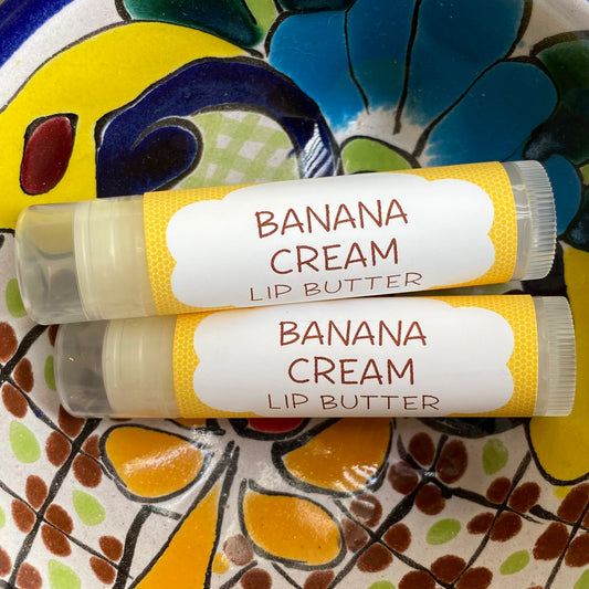 Two tubes of banana cream lip butter with yellow packaging on a colorful background