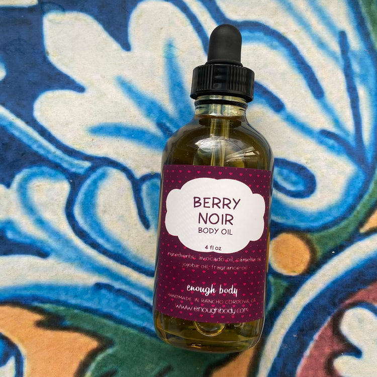 Bottle of Berry Noir body oil with a dropper on a colorful background