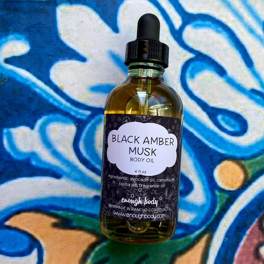 Bottle of Black Amber Musk body oil with a dropper on a colorful background