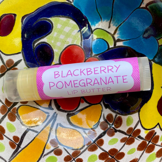 A tube of Blackberry Pomegranate Lip Butter placed on a colorful floral background.