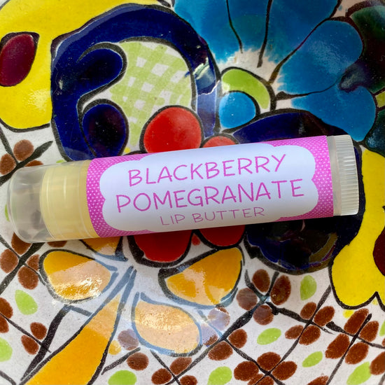 A tube of Blackberry Pomegranate Lip Butter placed on a colorful floral background.