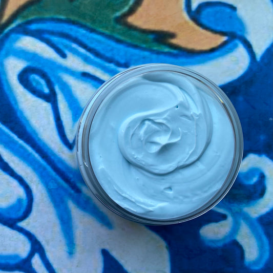 Jar of blue cream on a blue and green patterned fabric background