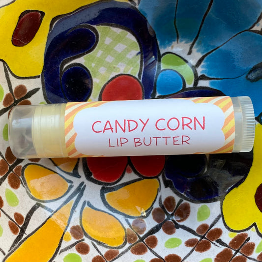 A tube of candy corn lip butter on a colorful background