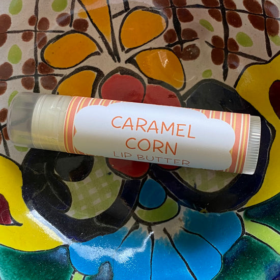 Lip butter labeled 'Caramel Corn' on a colorful ceramic plate