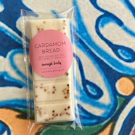 A wax melt snap bar with cardamom bread label, covered in glitter, placed on a colorful patterned background.
