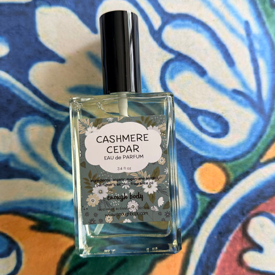 Perfume bottle labeled 'Cashmere Cedar' on a colorful patterned background