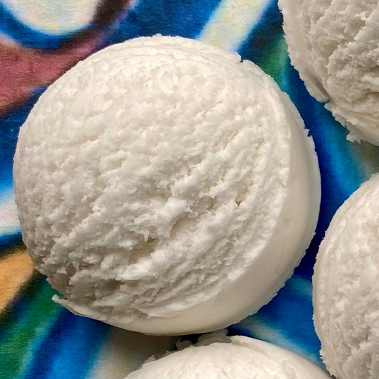 Solid white bubble bath scoop against a colorful, patterned background.