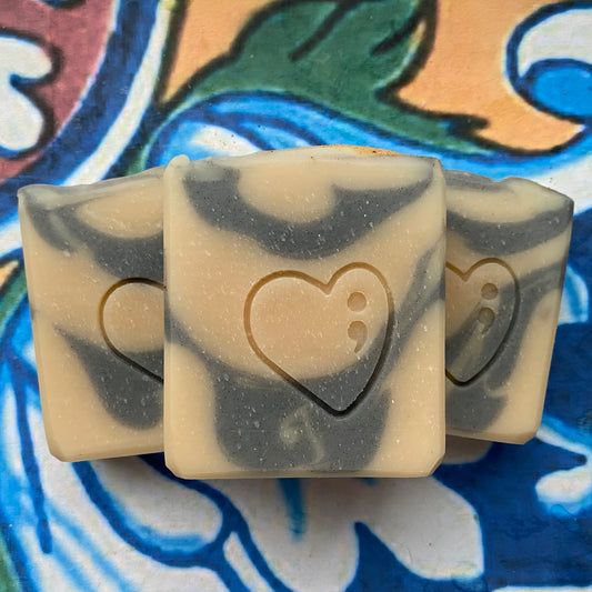 Three soap bars with a heart design on a colorful tile background