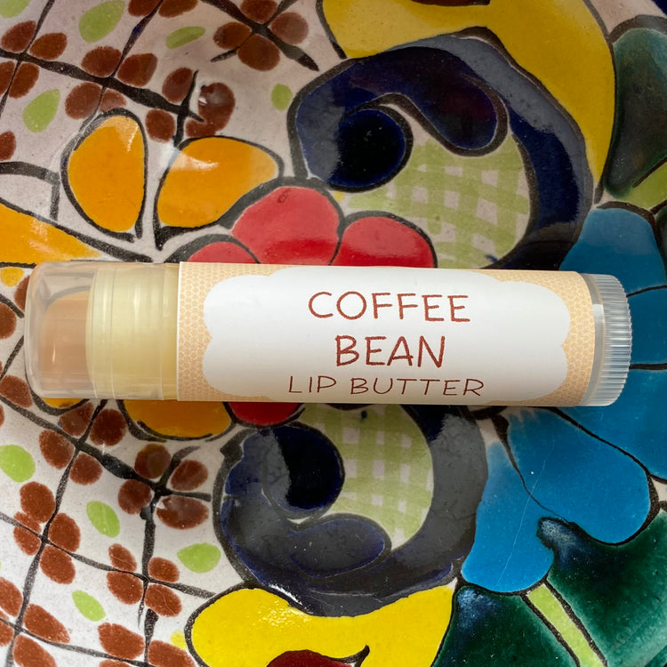 A tube of coffee bean lip butter with tan packaging on a colorful background