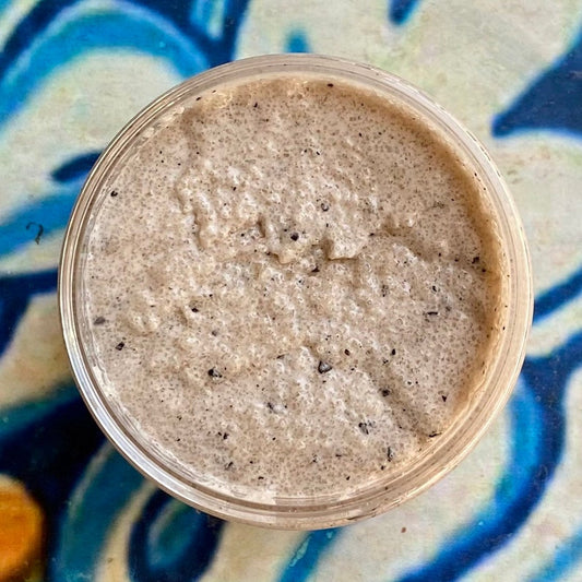 Close-up of a container of brown creamy substance on a blue and white patterned surface