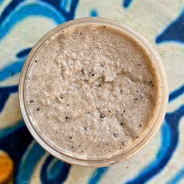 Close-up of a container of brown creamy substance on a blue and white patterned surface