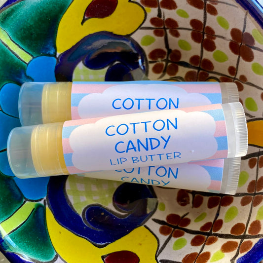 Three tubes of lip balm with 'Cotton Candy' labels, on a colorful ceramic dish with a floral pattern.