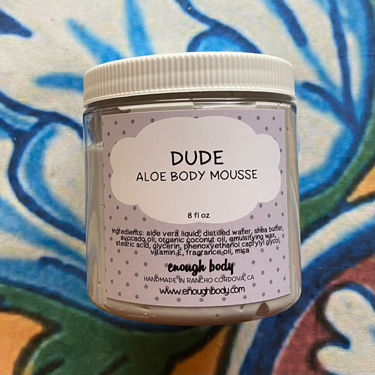 Jar of 'Dude Aloe Body Mousse' with a colorful abstract background