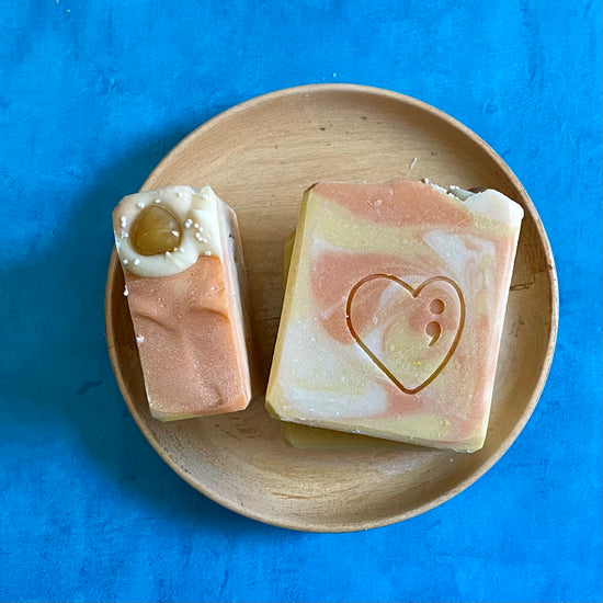 Yellow and orange square shaped soap bar on a plate sitting on a blue background