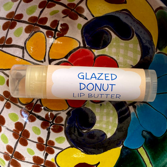 A tube of glazed donut lip butter on a colorful background