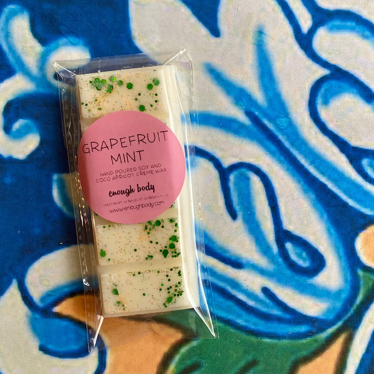 A wax melt snap bar with grapefruit mint label, covered in glitter, placed on a colorful patterned background.