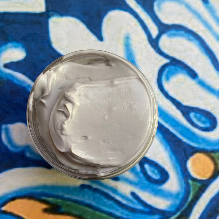 Close-up of a container with a gray colored cream on a colorful background