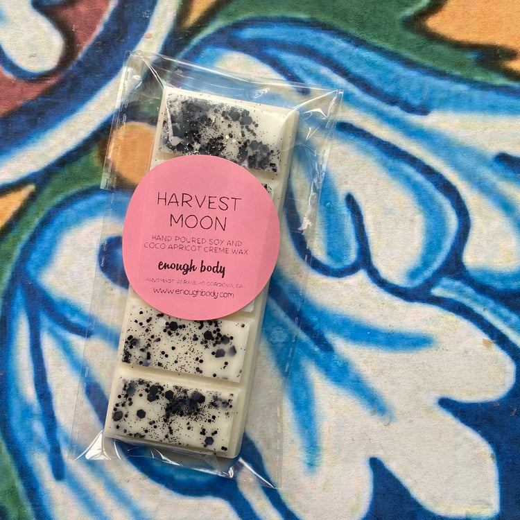 Packaged wax bars with a pink label on a colorful tile background