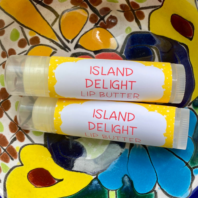 Two tubes of Island Delight Lip Butter placed on a colorful floral background.