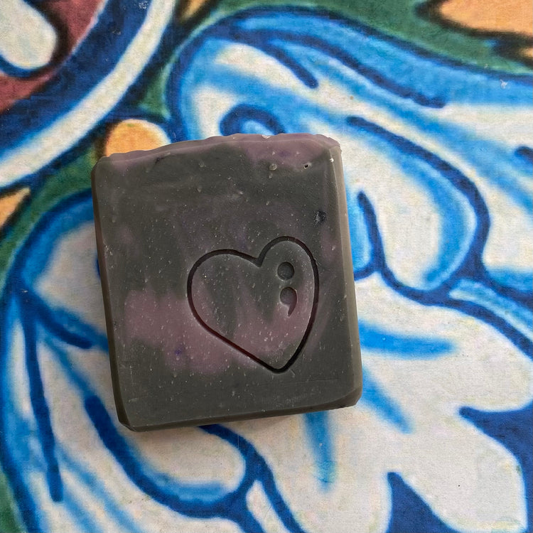 Black square object with a heart cutout on a colorful patterned surface