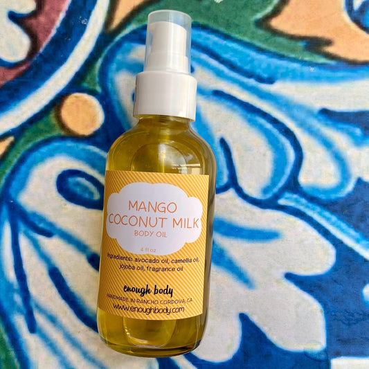 Bottle of Mango Oconut Milk scented body oil with a treatment pump top n a colorful background