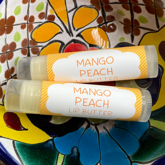 Two tubes of Mango Peach Lip Butter placed on a colorful ceramic plate with a floral pattern.