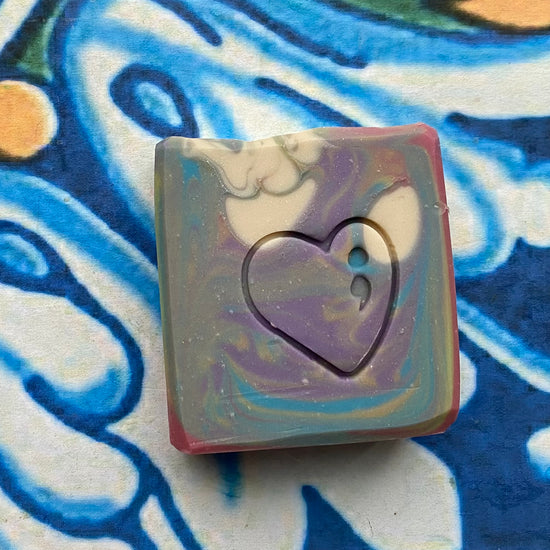 Multi colored square soap with a heart cutout on a colorful background