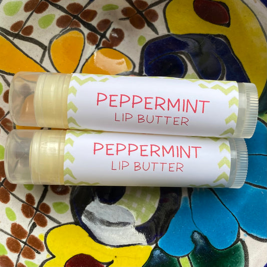 Two tubes of peppermint lip butter placed on a colorful plate with floral patterns.