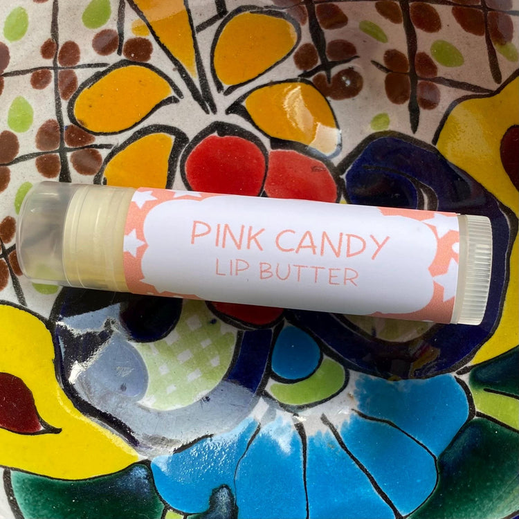 A tube of Pink Candy Lip Butter placed on a colorful floral background.