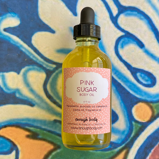 Bottle of Pink Sugar body oil on a colorful abstract background